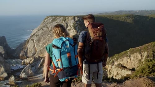 Couple of Hikers with Camping Backpacks Standing at Cliff