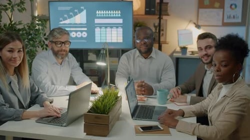 Slow Motion Portrait of Successful Business Team Sitting Indoors in Office Smiling