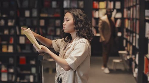 Asiatische Studentin liest Buch in der modernen Bibliothek
