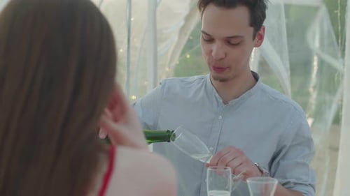 Man Pours Champagne for Woman in a Romantic Setting