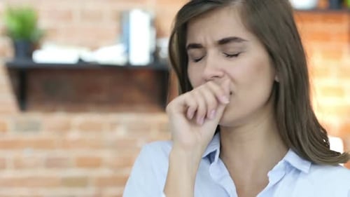 Young Woman Coughing Indoors Due to Illness