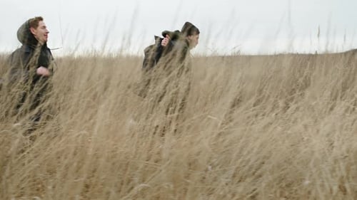 Two Friends Running Across The Field. They Bounce And Catch Up With Each Other.