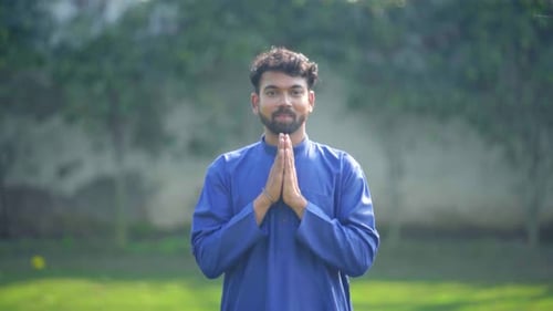 Man with Beard and Blue Tunic Prays in Field