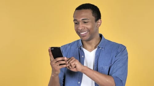 Young Adult Smiling While Using Smartphone