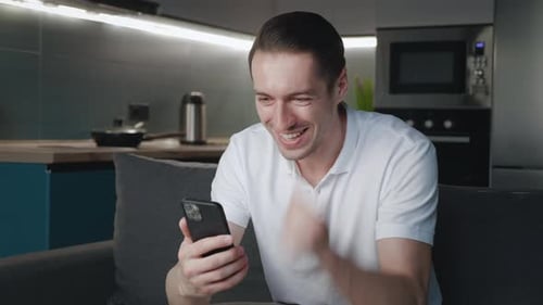 Man Reacts Positively While Using Mobile Phone at Home