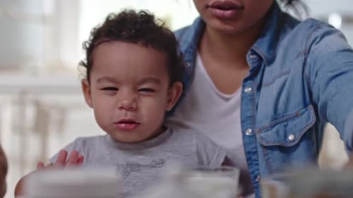 Mother Feeds Child Cracker in the Kitchen