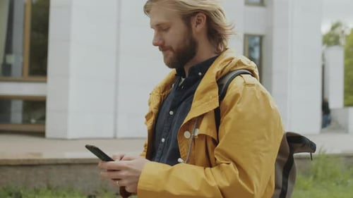 Man Walking in City and Using Smartphone