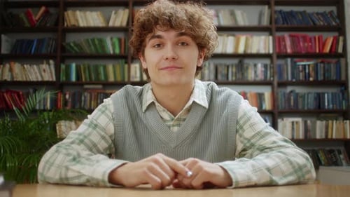 Smiling Man Speaking in Front of Bookshelves