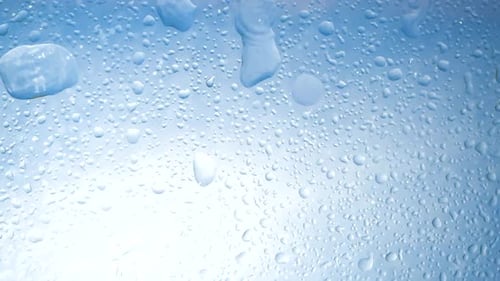 Falling Drops of Water Falling Down Create Splashes Against Background of Blue Sky and Bright Sun