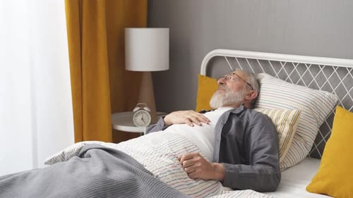 Senior Man Lying in Bed with Headache