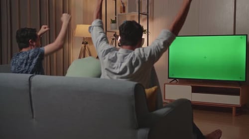 Happy Time Of Young Friends Cheering And Watching Green Screen Tv And Celebrating Victory At Home