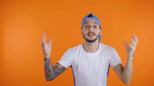 Surprised Young Adult Expressing Shock on Orange Backdrop