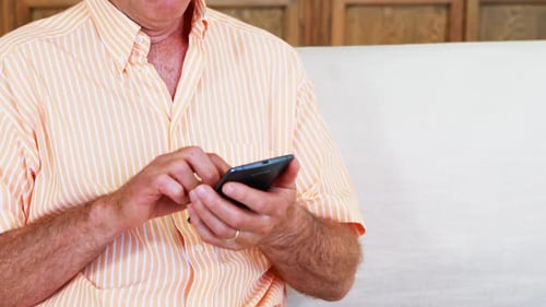 Senior Adult Using Smartphone on Couch Indoors