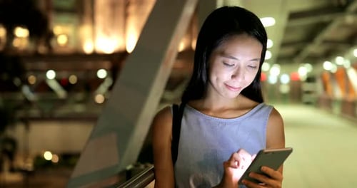 Woman use of mobile phone in city at night