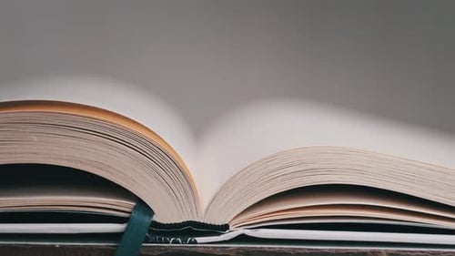 Hand Turns Pages of Open Book in Close Up