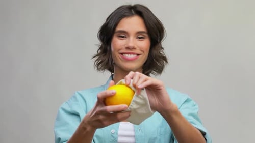 Mujer feliz poniendo limón en una bolsa de lona reutilizable