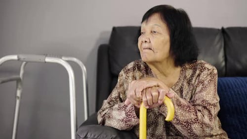 Senior Woman Sitting with Cane in Living Room