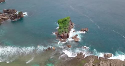 Tiro de Drone da ilha de Coral coberta por árvores verdes que são atingidas pelas ondas batendo no t