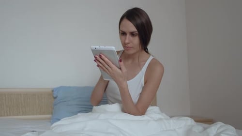 Young Woman Using Tablet in Bed