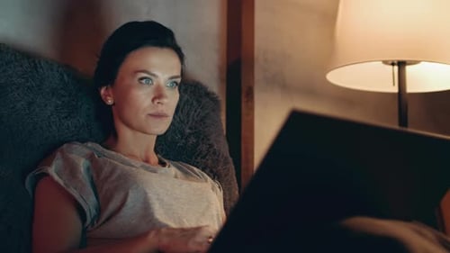 Woman Using Laptop in a Dimly Lit Room