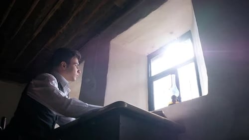 Writer Sits at Desk in Dark Room