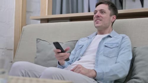 Man Excitedly Watching Television on Couch