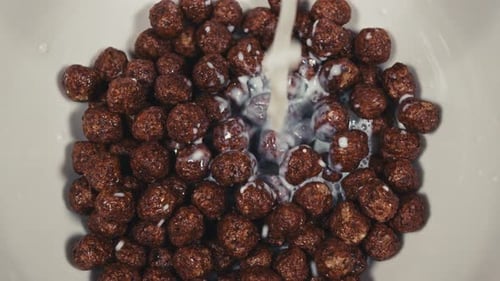 Milk Pouring onto Chocolate Cereal in a Bowl