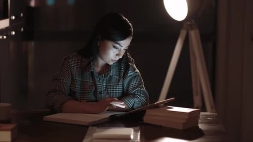 Young Woman Works on Tablet at Dark Desk
