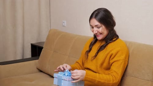 Excited Woman Receives Birthday Gift on Sofa