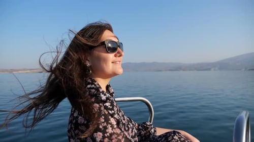 Young Woman Stands on Boat Bow Sailing Along Calm Blue Lake