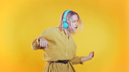 Enthusiastic Young Person Dancing in Front of Yellow Backdrop