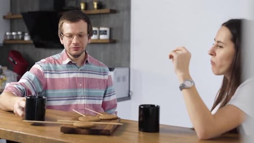 Couple Drinking Coffee and Eating at Kitchen Counter