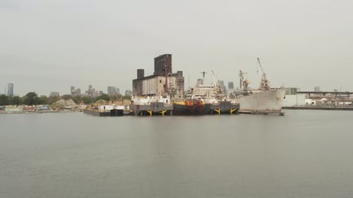 Over Rusty Old Cargo Ships and Old Warehouse in the Docks of New York City on a Cloudy Grey