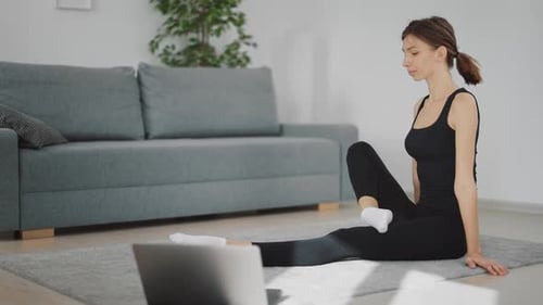 Woman Does Stretching Exercises on Yoga Mat Indoors