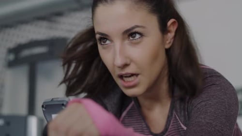 Handheld view of tired woman exercising in the gym. Shot with RED helium camera in 8K