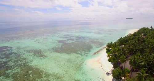 Aerial drone view of a scenic tropical island resort hotel in the Maldives.