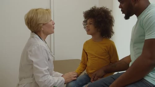 Doctor Talking With Child Patient and Father in Office