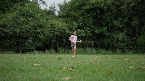 Zeitlupe, Fröhliches kleines Mädchen, das im Park rennt und lächelt