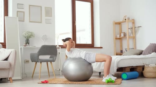 Woman Does Sit-ups on Exercise Ball at Home