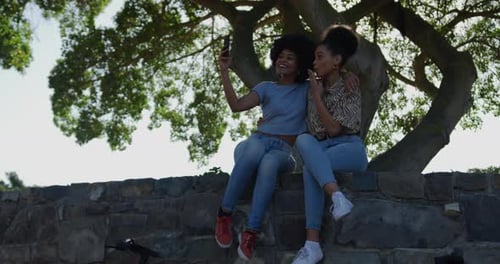 Zwei Frauen gemischter Rassen fotografieren im Park