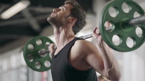 Athlete Man Squatting with Weight Barbell at Bodybuilding Training in Gym