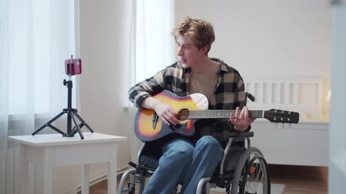 Young Man Plays Guitar and Sings at Home