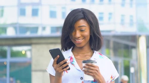 Smiling Woman Uses Smartphone Outdoors in City