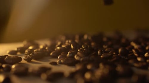 Makroaufnahme von Kaffeebohnen, die in Zeitlupe auf den Tisch fallen