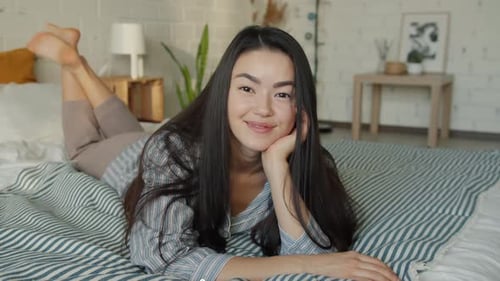 Woman Relaxing on Bed in Pajamas Smiling