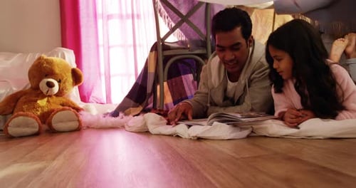 Dad Reads to Daughter in Cozy Blanket Fort