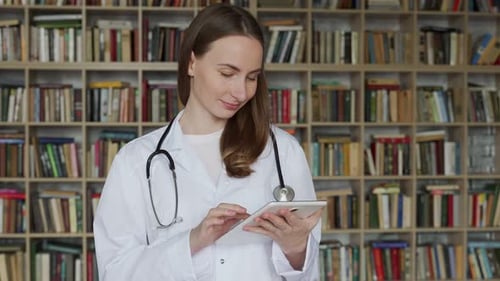 Female Doctor Works with a Laptop and Studies Some Information About Medicines in a Consultation