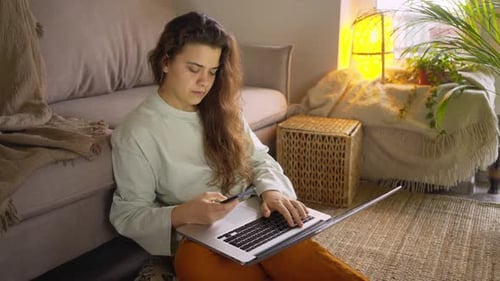 Woman Using Laptop and Phone at Home