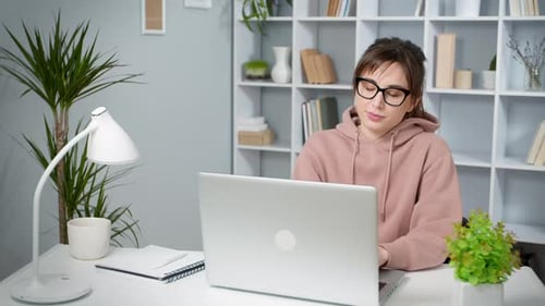 Young Woman Typing on Laptop at Desk in Home
