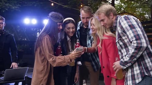 Friends Gathered Around Smartphone at Outdoor Night Party